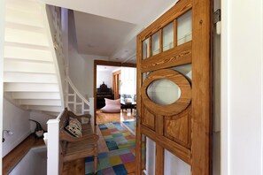 Eine Treppe mit Holzwand, einem farbenfrohen Teppich und einer Holztür mit Glasfeldern.