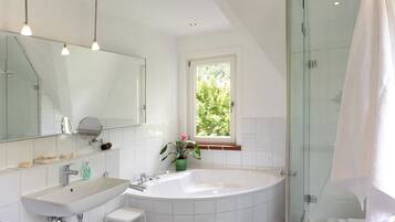 A modern bathroom with a large bathtub, a separate shower area, and a window providing natural light.