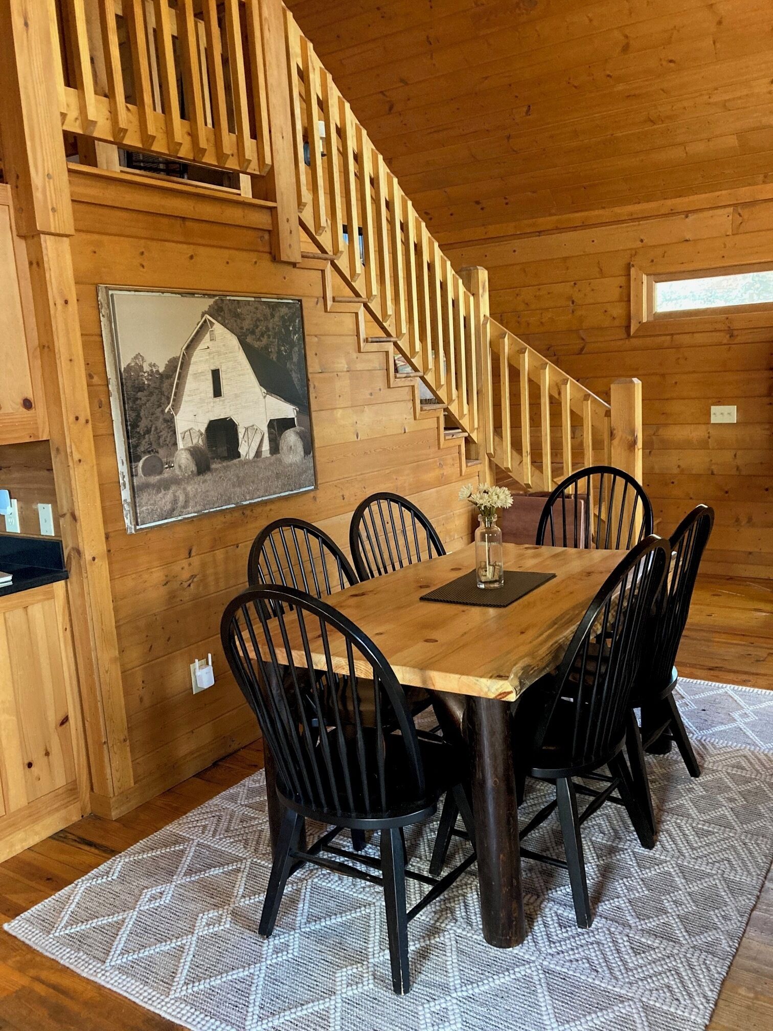 A wooden dining area with a table and chairs, a staircase, and a framed picture on the wall.