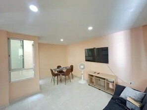 Cozy living space with a dining and seating area, featuring a flat-screen TV, fan, and table with chairs.