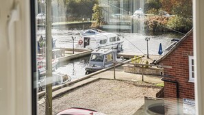A canal with boats docked, a brick building, and a signboard. - A perfect waterside setting. (Horning)