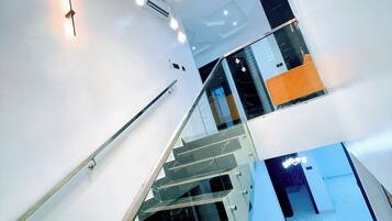 A modern staircase with glass railings and a chandelier.
