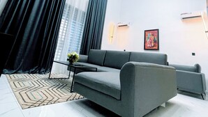Un salon moderne avec un canapé gris, un tapis à motifs et un luminaire décoratif.