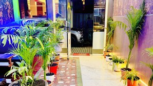 Un hall de hotel con piso de baldosas, plantas en macetas y un gran mural en la pared.