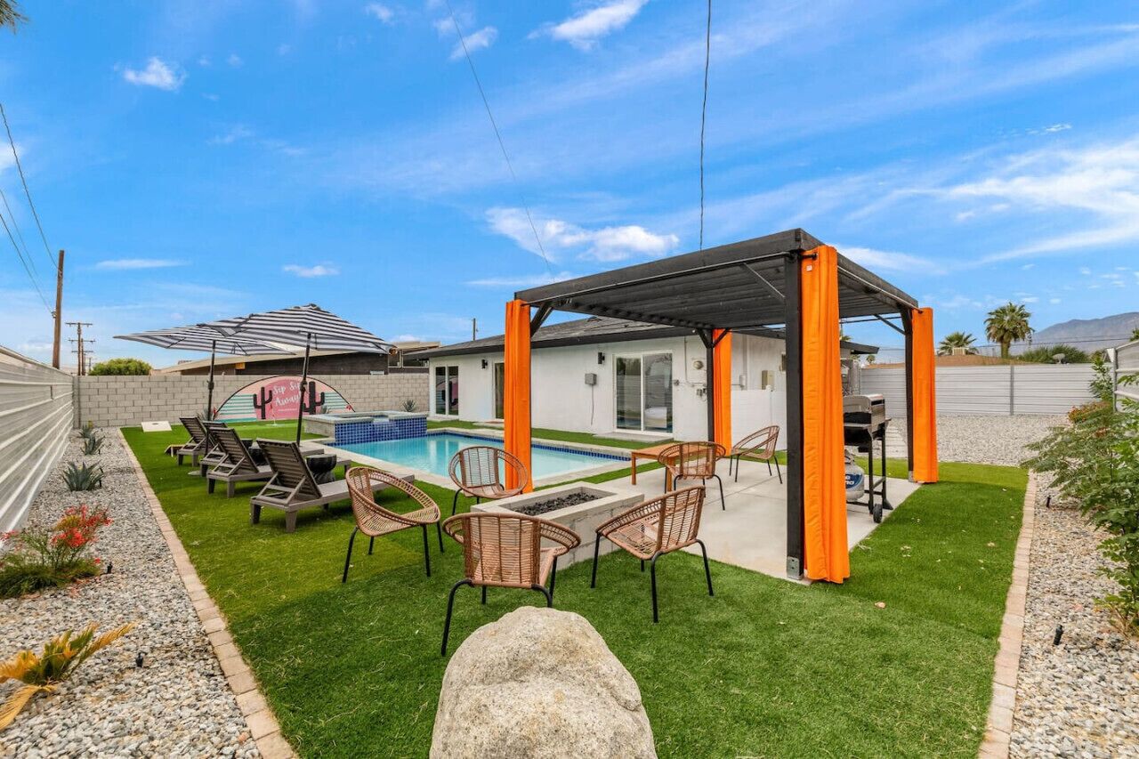 A backyard with a swimming pool, outdoor seating, and a covered patio area.