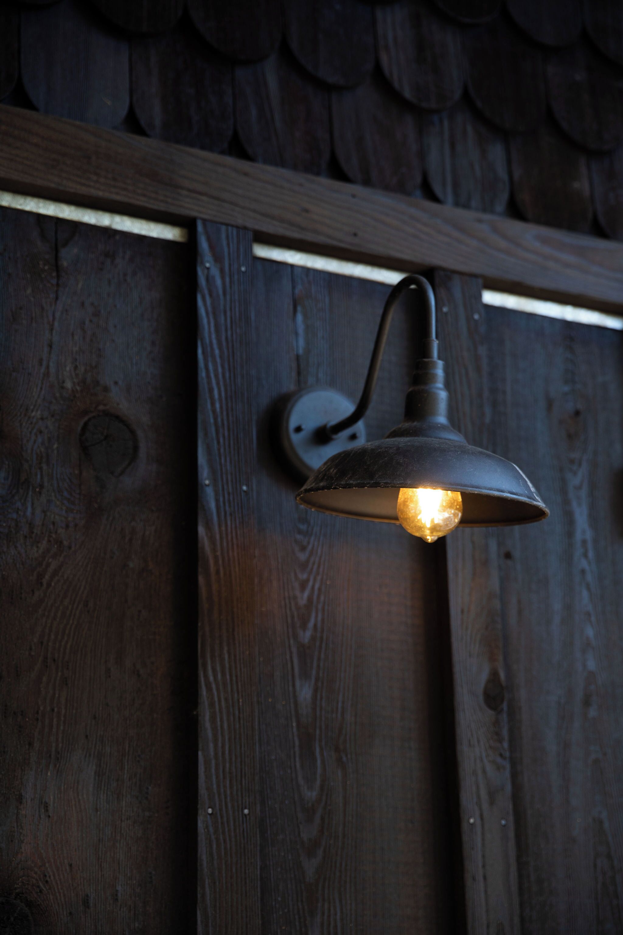 A wall-mounted light fixture with a visible bulb, attached to a wooden surface with a horizontal beam above.