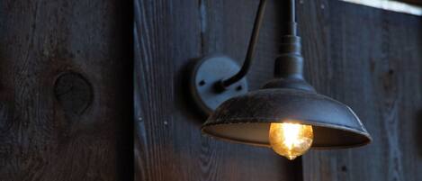 A wall-mounted light fixture with a visible bulb, attached to a wooden surface with a horizontal beam above.