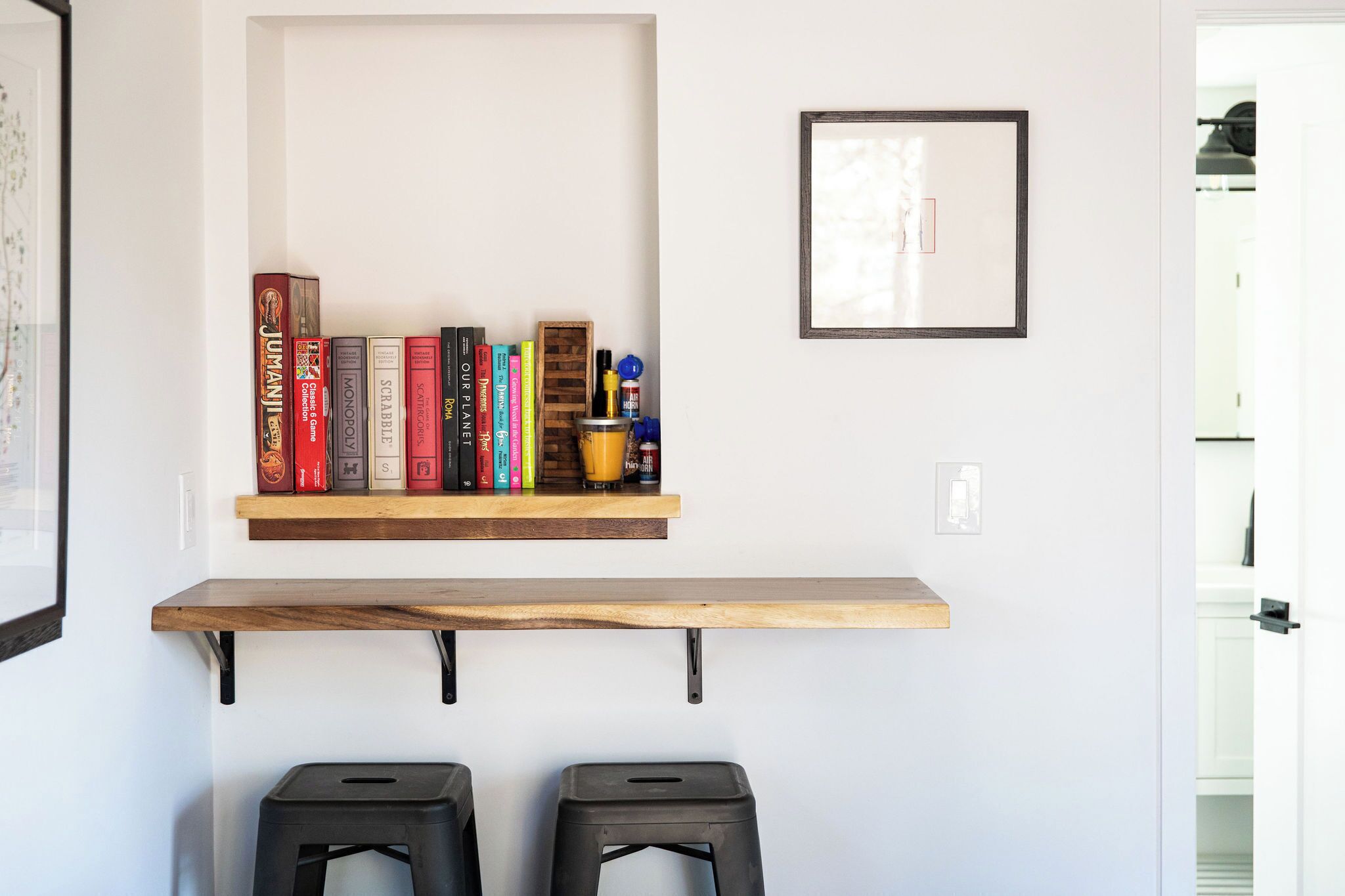 A room with a wooden shelf holding books and a framed picture on the wall.
