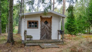 A small cabin with a wooden door, a window, and a bench outside. - Beautiful home in Muskö with WiFi (Muskö)