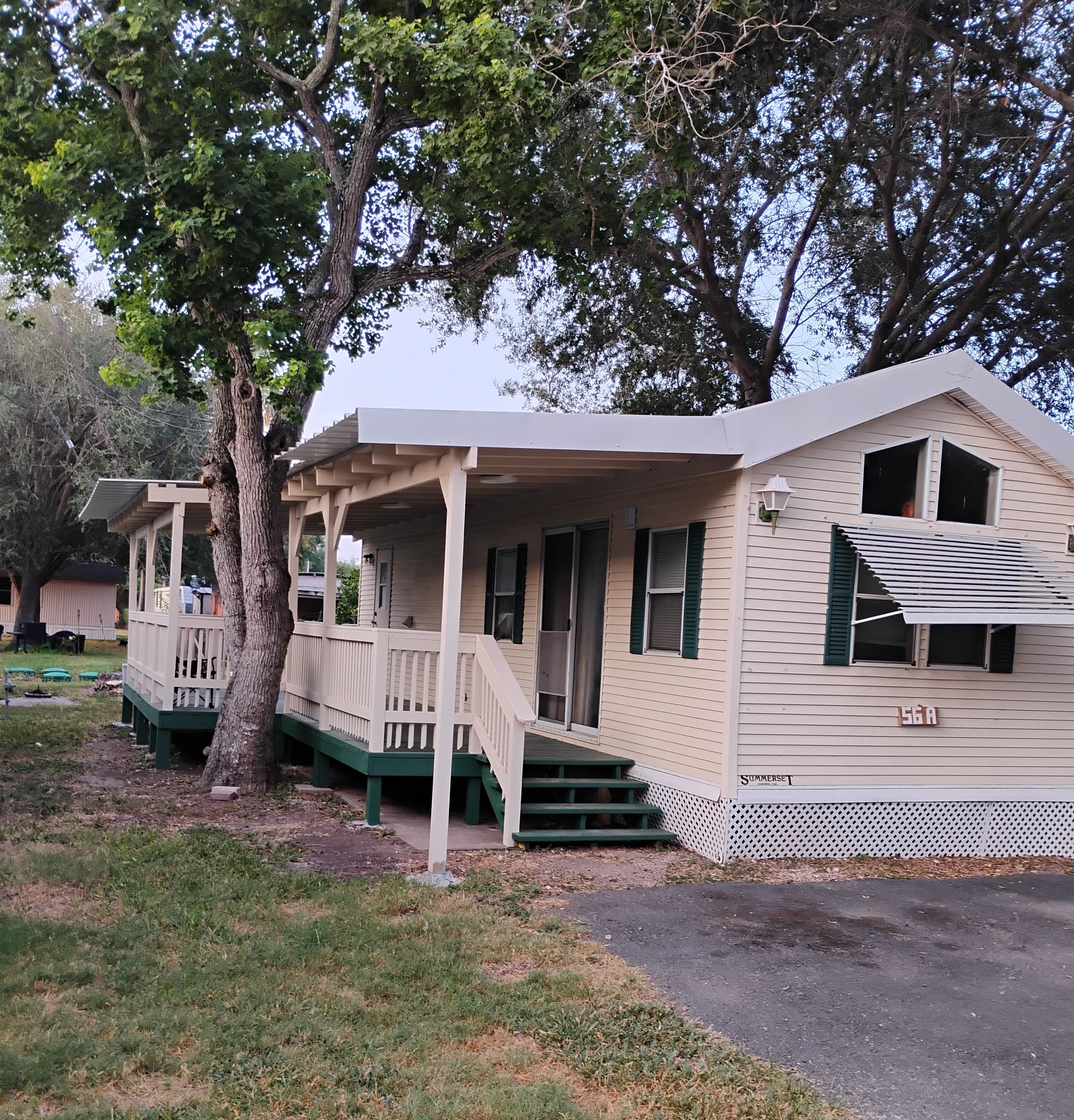A single-story house with a porch, a covered outdoor seating area, and a small deck.