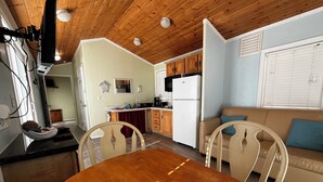 A compact kitchen with wooden cabinets, a dining table, and a sofa.