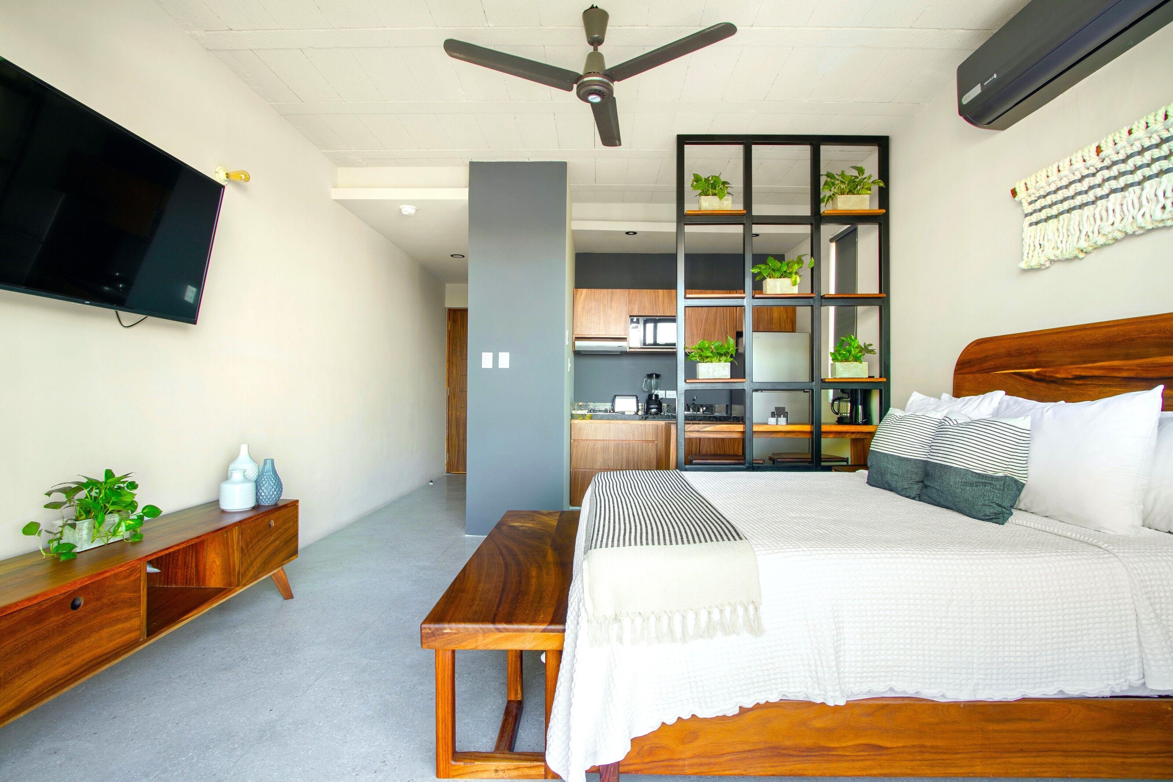 A modern bedroom with a bed, bedside table, and a TV mounted on the wall.