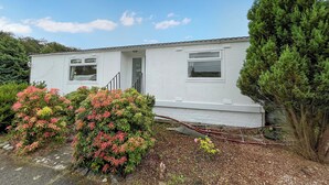 A single-story house with a white exterior, a front door, and a small porch. - 3 bedroom accommodation in Newton Stewart (Newton Stewart)