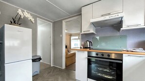 A compact kitchen with a refrigerator, oven, and a microwave. - 3 bedroom accommodation in Newton Stewart (Newton Stewart)