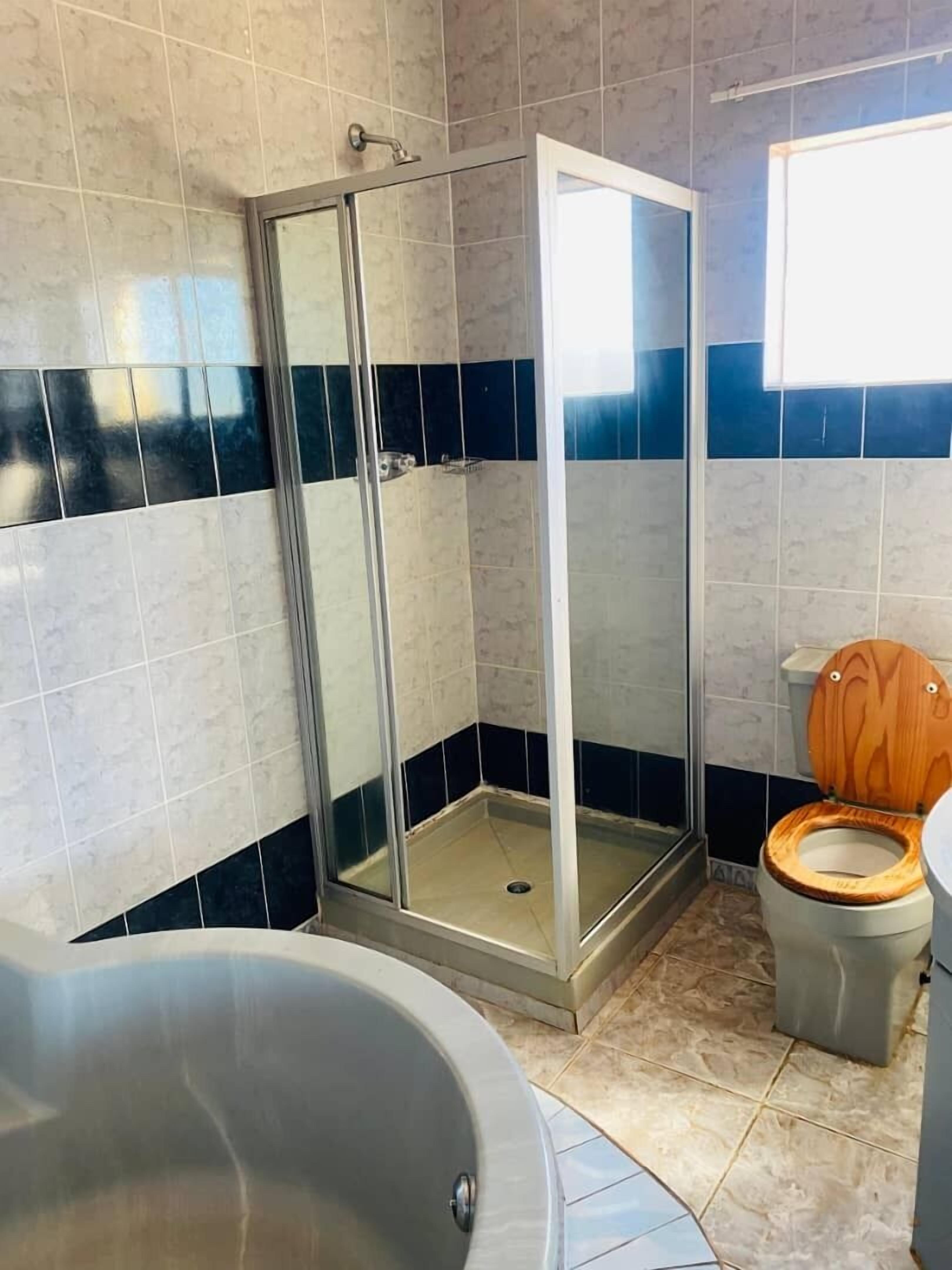 Une salle de bain avec une douche à parois de verre, des toilettes en bois et une baignoire.