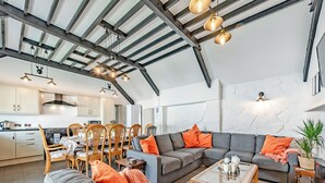 Un'ampia zona giorno con un grande divano componibile, un tavolino da caffè e un'area pranzo con sedie e tavolo in legno.