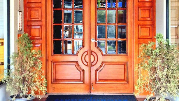 A wooden double door with glass panels, flanked by potted plants, leading to a tiled entrance area. - Spacious 3-bedroom apartment in lovely Quito with WiFi (Quito)