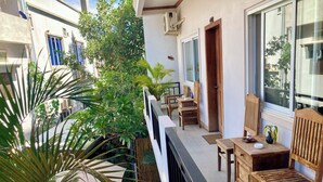 Un balcon agrémenté de meubles en bois, de plantes en pot et offrant une vue sur les bâtiments voisins.