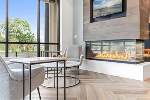 Ein modernes Wohnzimmer mit großem Fernseher, Kamin und Essbereich mit Tisch und Stühlen.