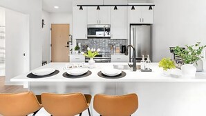 Een moderne keuken met witte kastjes, een centraal eiland en een roestvrijstalen koelkast.