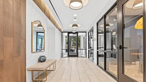 Een moderne hal met een bank, glazen deuren en een plafond met ingebouwde verlichting.