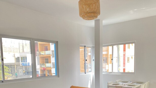 Una sala de estar moderna con un sofá gris, cojines amarillos, una mesa de centro de madera y una lámpara colgante de fibras naturales.