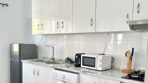 Una cocina moderna con armarios blancos, lavadora integrada, microondas, estufa y refrigerador.