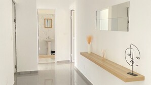 Un pasillo moderno con un banco de madera, un espejo y una obra de arte minimalista.