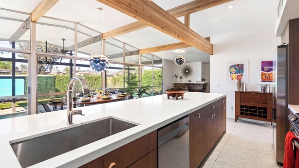 A modern kitchen with a large island, wooden beams, and a view of a pool. - Mid Century Modern home -newly renovated with swim jet pool, spa on golf course! (Palm Desert)