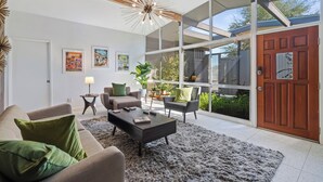 A modern living room with a large window, a wooden ceiling, and a central coffee table. - Mid Century Modern home -newly renovated with swim jet pool, spa on golf course! (Palm Desert)