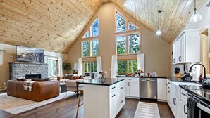 A spacious kitchen with white cabinets, a central island, and large windows. - Large Trendy Chalet, HotTub, Sleeps 14, Arcade! (Bethel)
