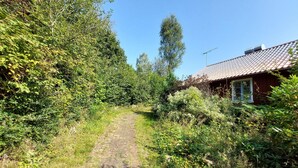 A narrow dirt path leading to a rustic house with a tiled roof, surrounded by dense greenery and trees. - 4 bedroom cozy apartment in Höör (Höör)
