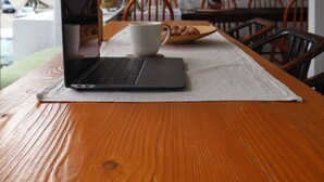 Une table en bois avec un ordinateur portable, une tasse et une assiette de croissants.