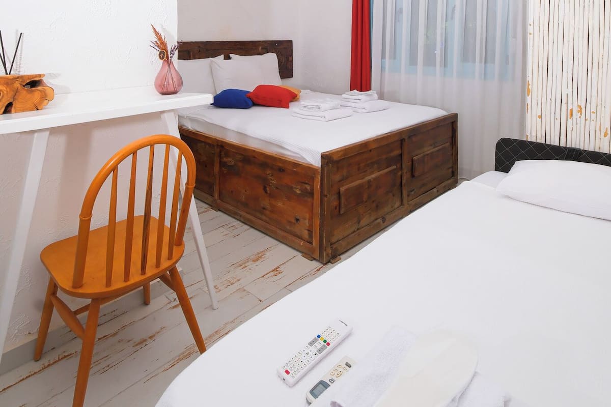 A bedroom with a wooden bed, a desk with a chair, and a bedside table with a lamp.