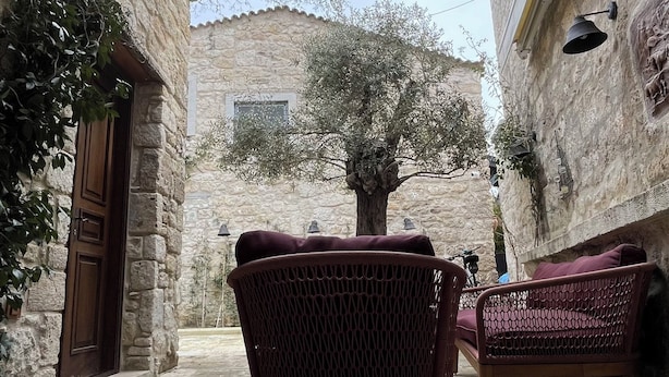 Un espace extérieur aménagé avec des murs en pierre, un grand arbre et un luminaire suspendu.