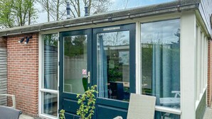 Una veranda con porta in vetro, parete in mattoni e tetto in metallo.