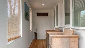 Un corridoio stretto con panche in legno, una scopa e un quadro appeso al muro.