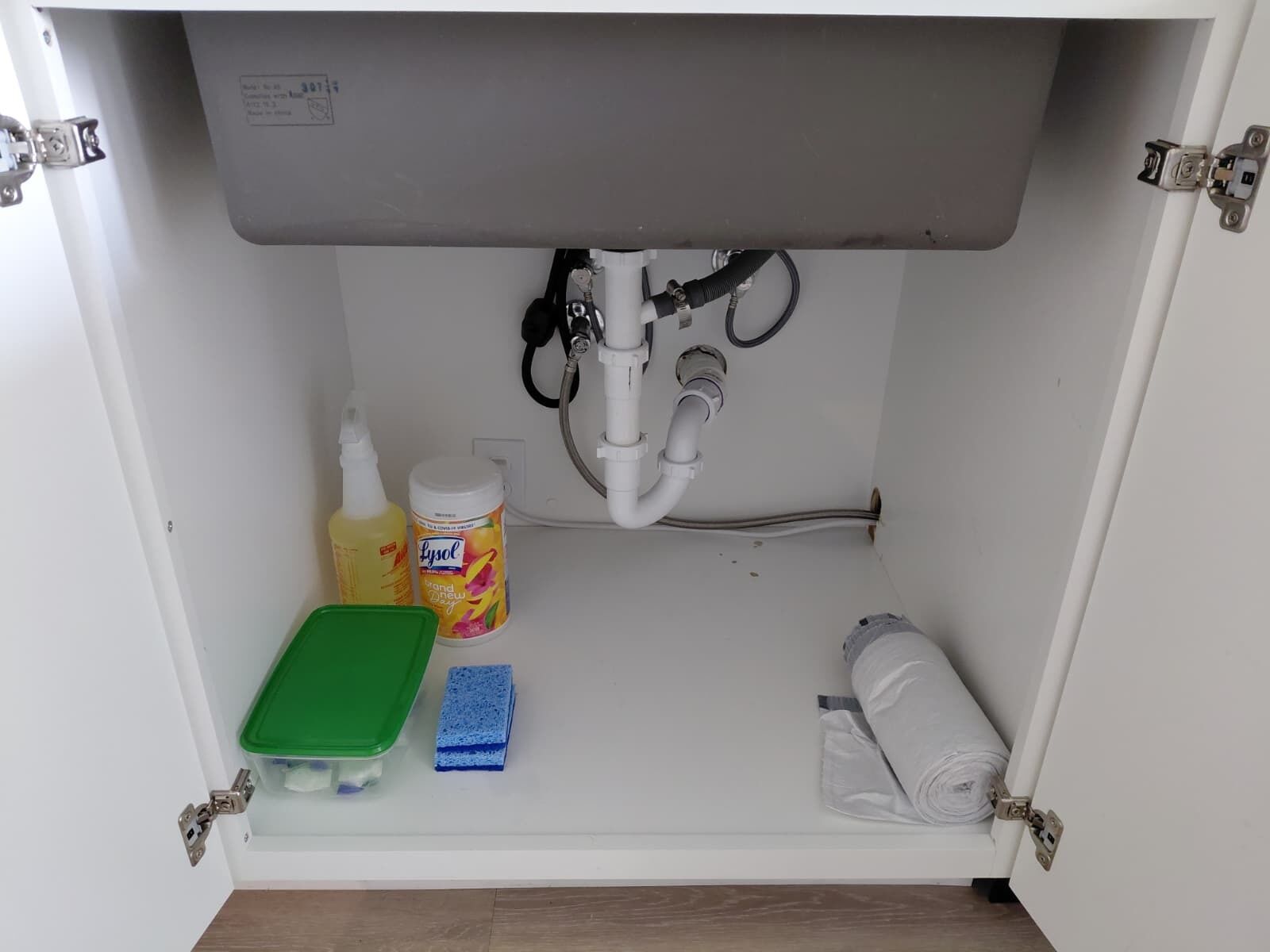En diskho med ett grönt diskställ, en flaska Lysol, en blå svamp och en hoprullad handduk.