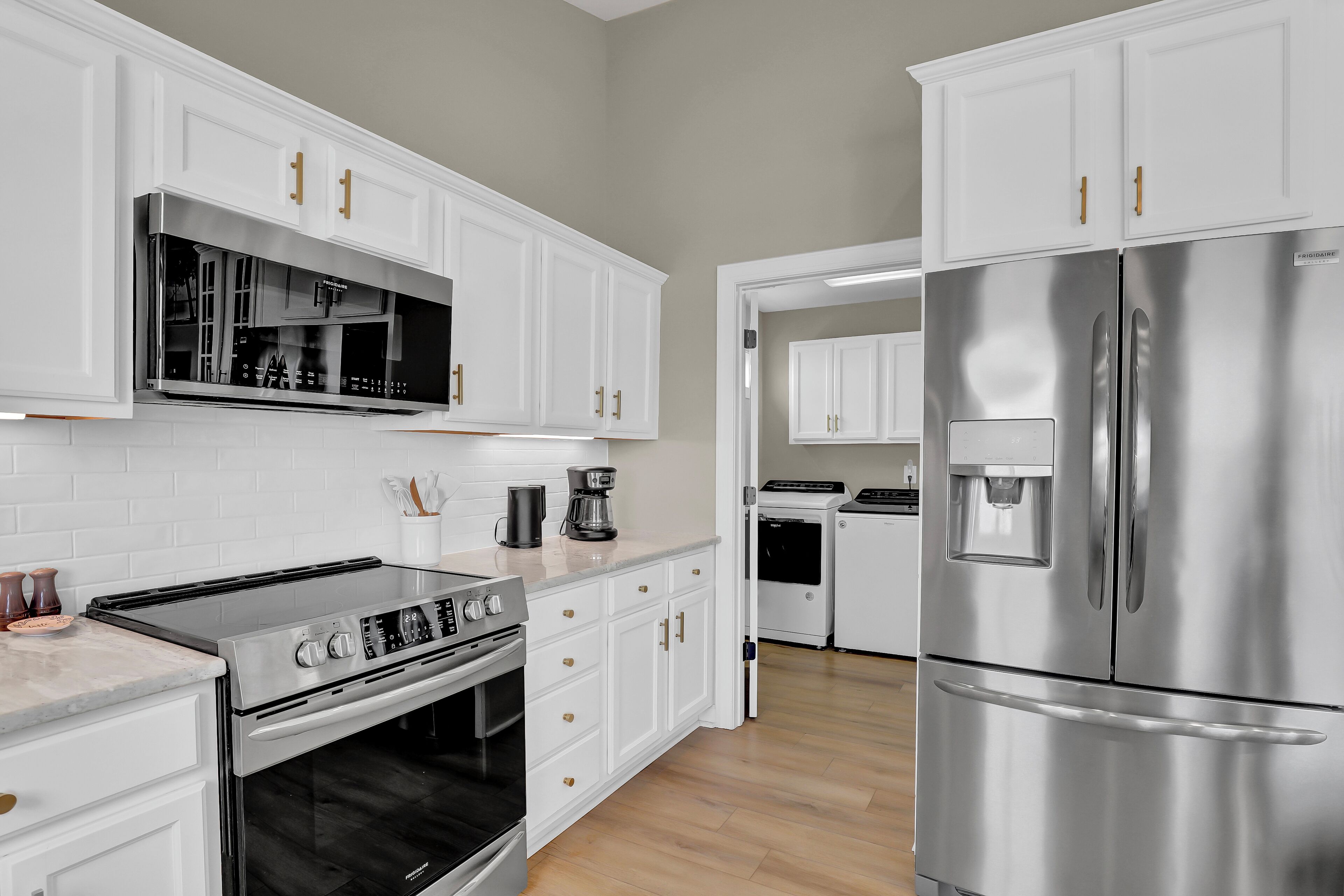Una cocina moderna con armarios blancos, electrodomésticos de acero inoxidable y horno empotrado.