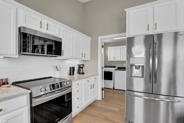 A modern kitchen with white cabinets, stainless steel appliances, and a built-in oven.