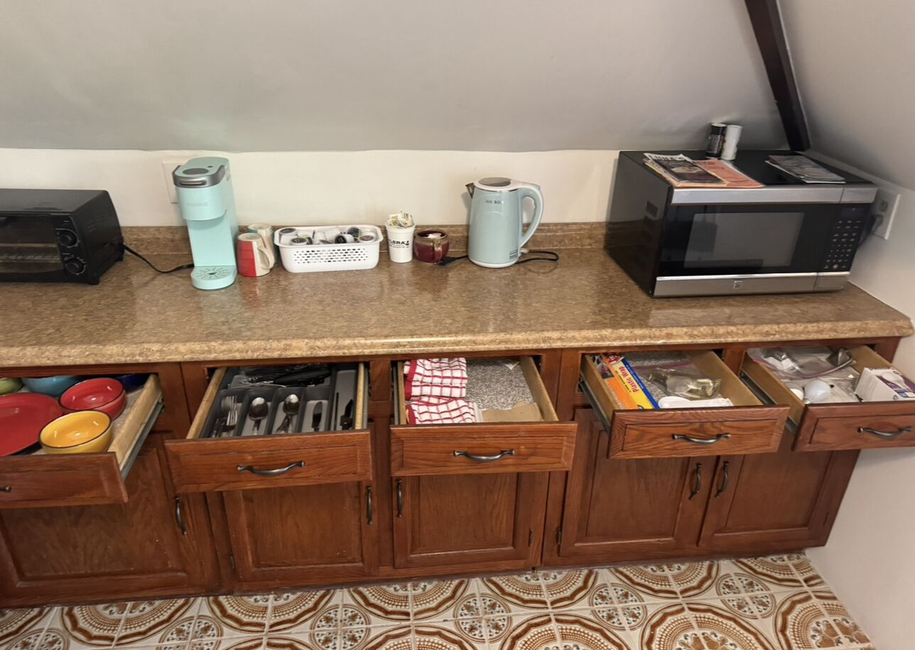 A kitchen with a microwave, kettle, and various kitchen utensils on the counter.