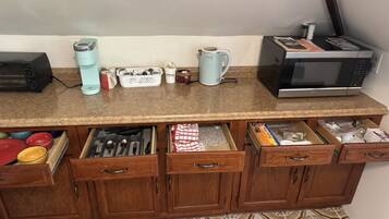 A kitchen with a microwave, kettle, and various kitchen utensils on the counter.