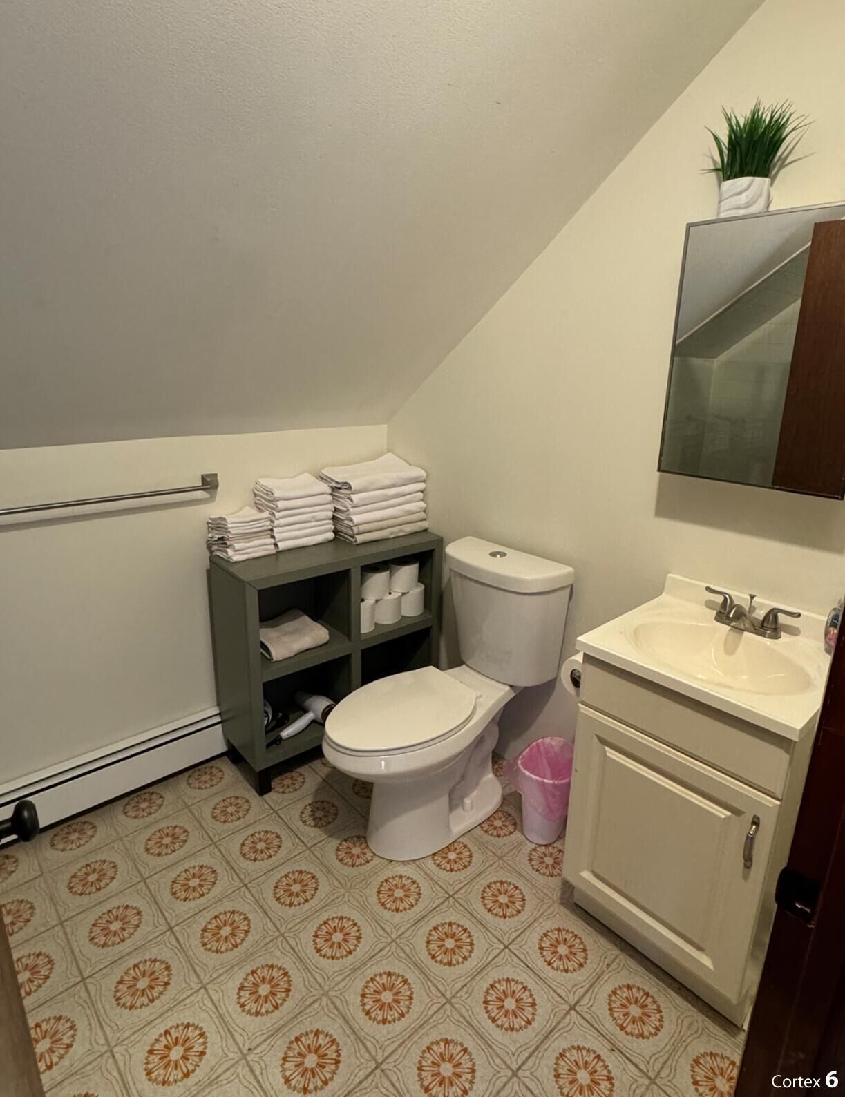 Un baño con inodoro, lavamanos y repisas con toallas.