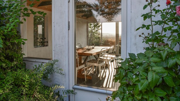 A dining area with a wooden table and chairs, a window with a view of trees, and a door leading to another room. - 2 bedroom beautiful home in Glemmingbro (Glemmingbro)