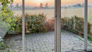 A view from a window overlooking a brick patio with a garden and fields in the distance. - 2 bedroom beautiful home in Glemmingbro (Glemmingbro)
