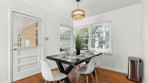 A dining area with a black table, white chairs, and a hanging light fixture.