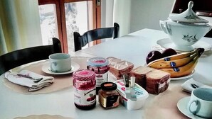 Et spisebord dækket med forskellige spiser, herunder syltetøjsglas, et brød og en banan.