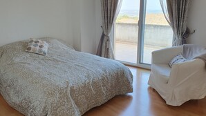 Un dormitorio con una cama, una silla y vistas al exterior por una puerta corrediza.