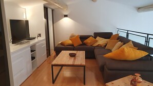Una sala de estar moderna con un sofá, una mesa de centro y un televisor sobre un mueble.