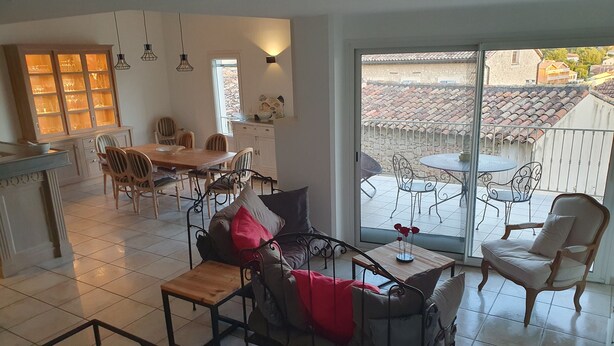 Un espacio habitable amplio con una mesa de comedor, sillas, un sofá y un balcón con mobiliario exterior.